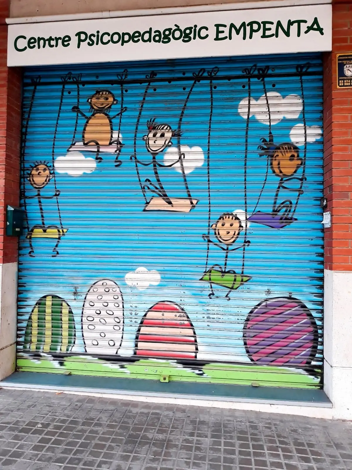 Entrada del Centre Psicopedagògic EMPENTA en Polinyà, con la persiana pintada
