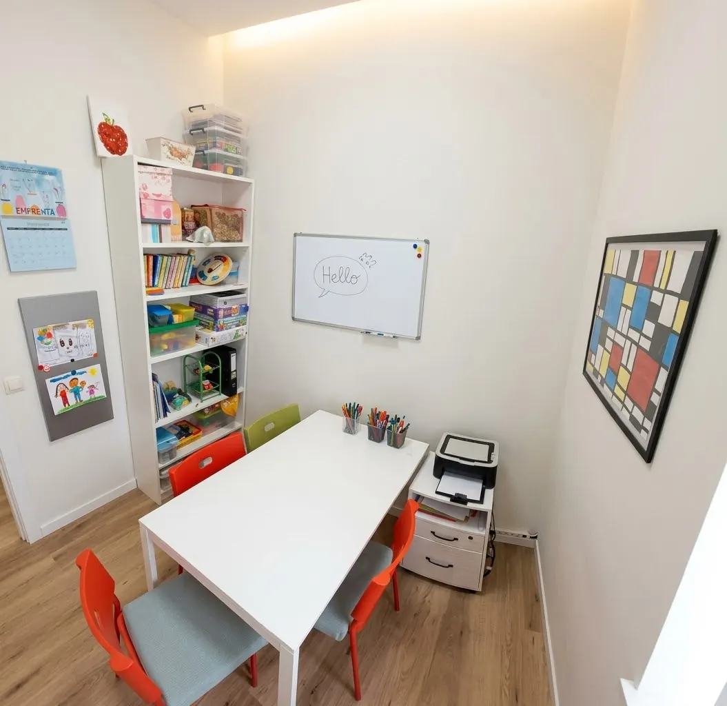 Sala de trabajo con mesa, estantería de materiales y pizarra
